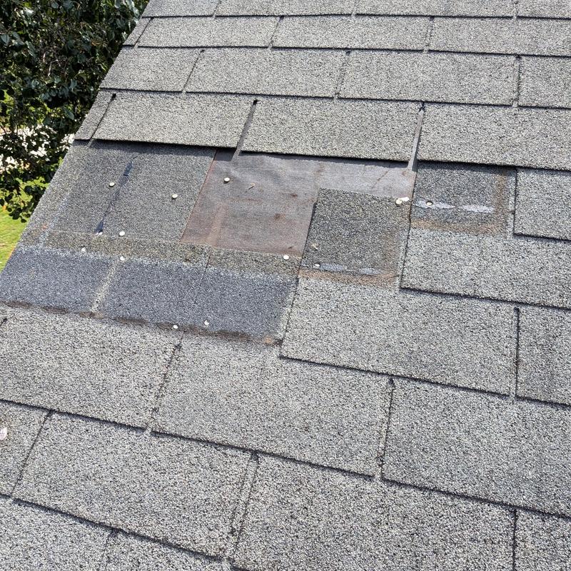 Asphalt shingles with replaced damaged section on roof