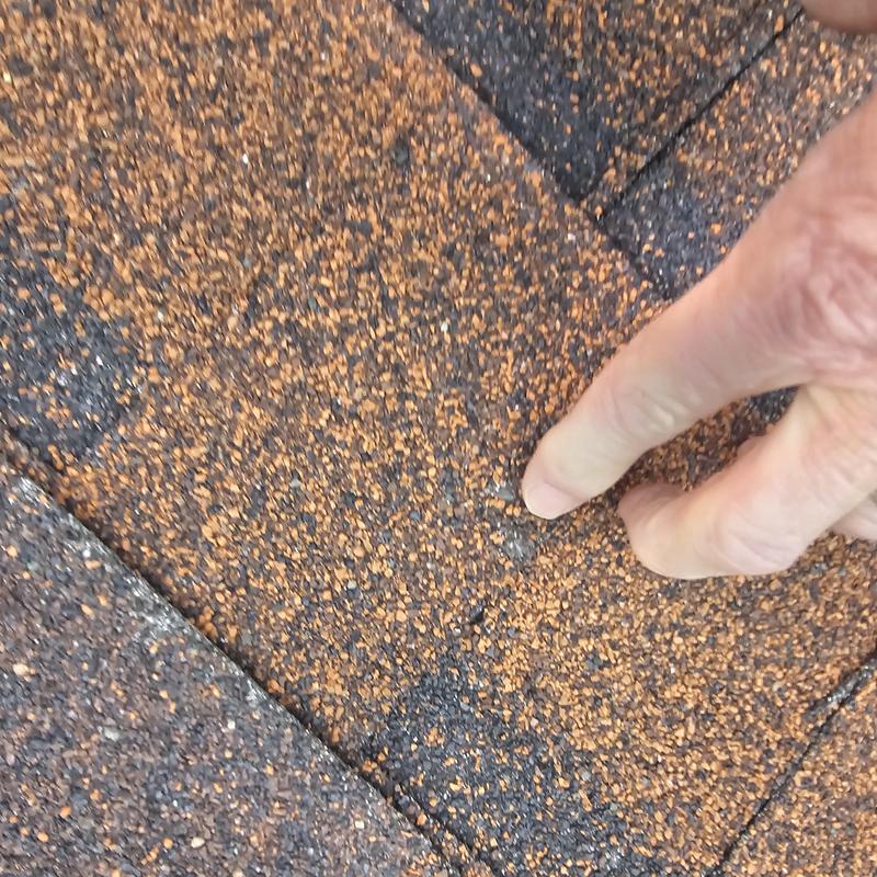 Roof shingle hail damage pointed out by hand