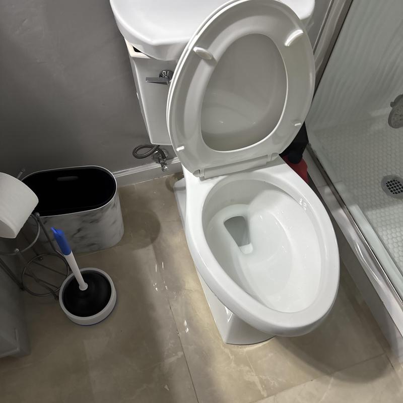 Toilet bowl with open lid and plumbing auger nearby
