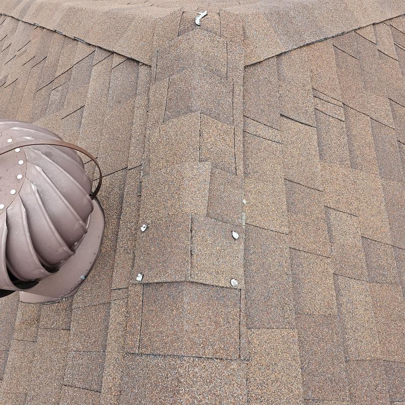 Asphalt shingle roof with hail damage near vent turbine