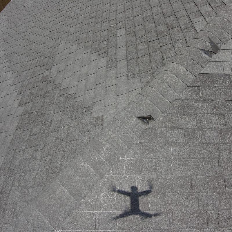 Shingles with wind damage and missing pieces on roof Shingles with wind damage and missing pieces on roof