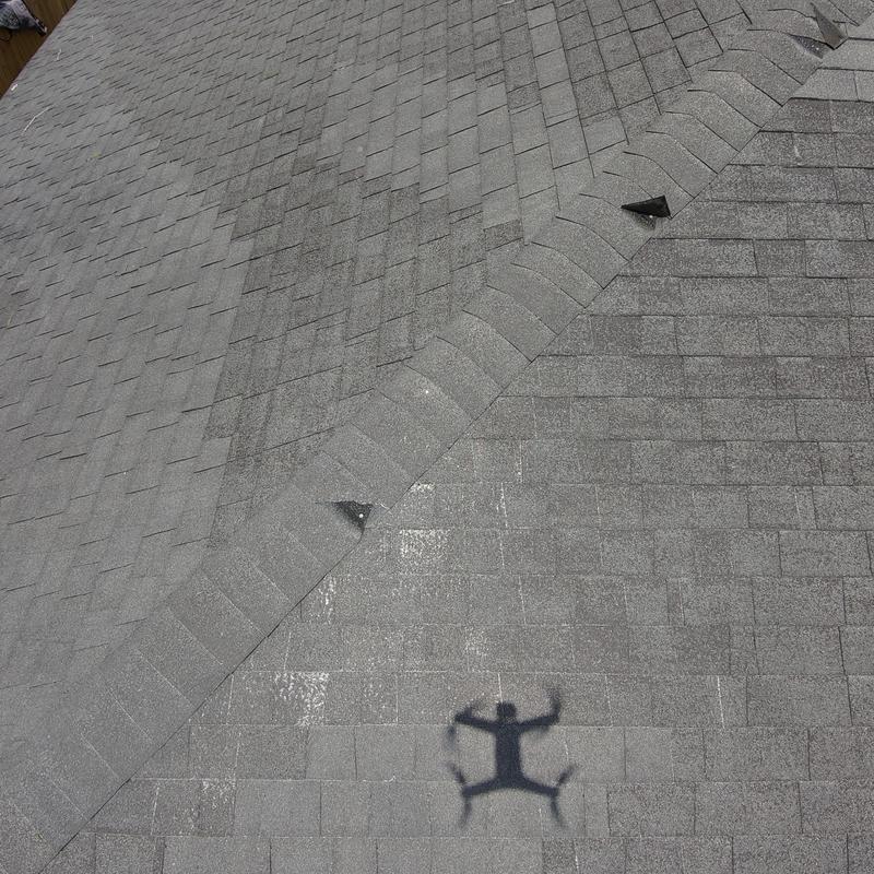 Roof shingles with wind damage shown by drone shadow Roof shingles with wind damage shown by drone shadow