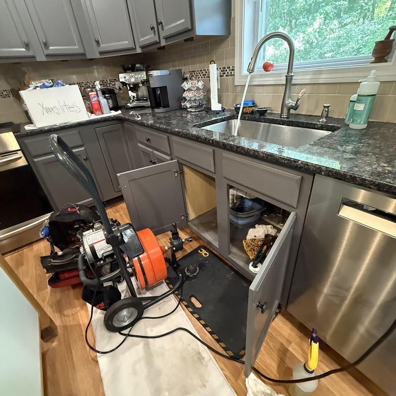 Kitchen sink drain with plumbing snake and open cabinets Kitchen sink drain with plumbing snake and open cabinets