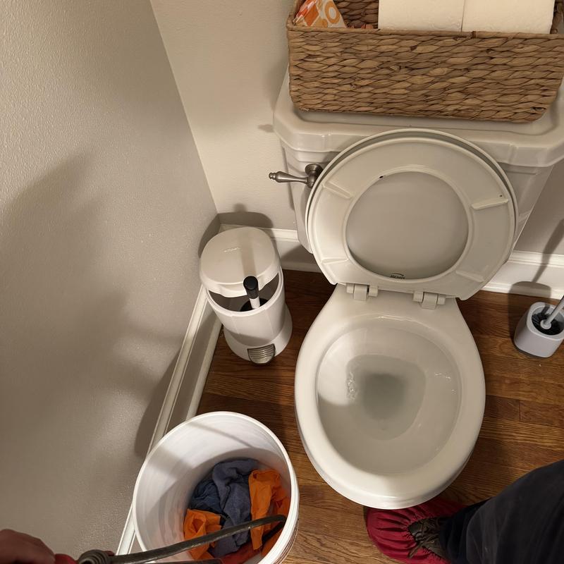 Toilet clogged with auger in bucket in bathroom corner Toilet clogged with auger in bucket in bathroom corner