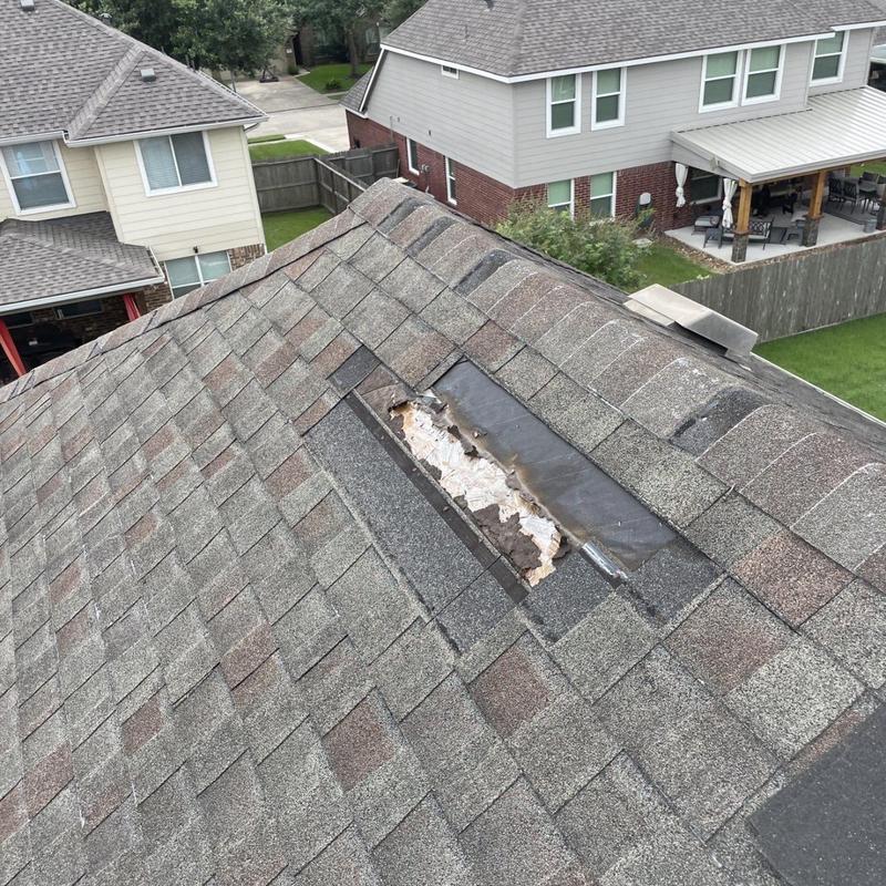 Damaged roof shingles and exposed decking on residential roof