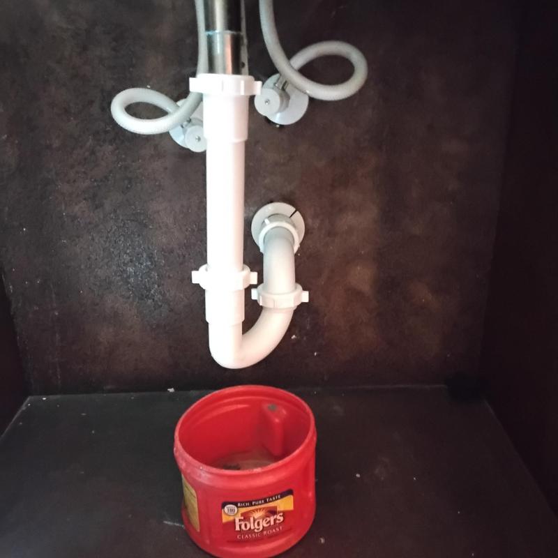 Lavatory sink drain pipes with red container beneath