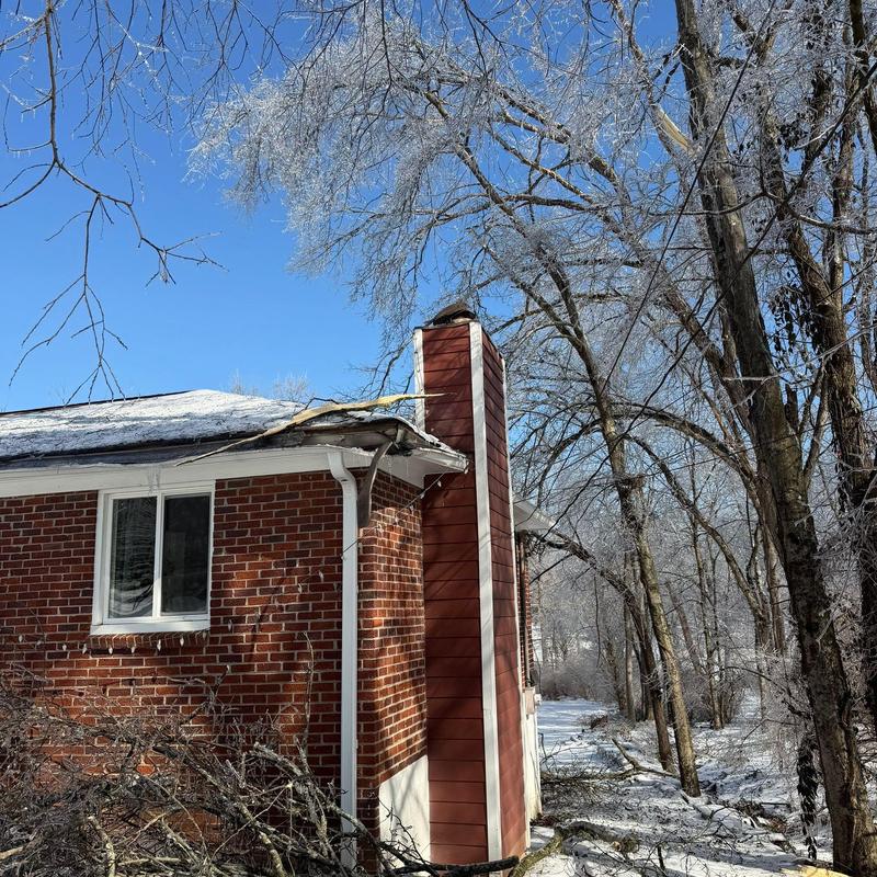 Roof shingles with ice and snow buildup on house edge