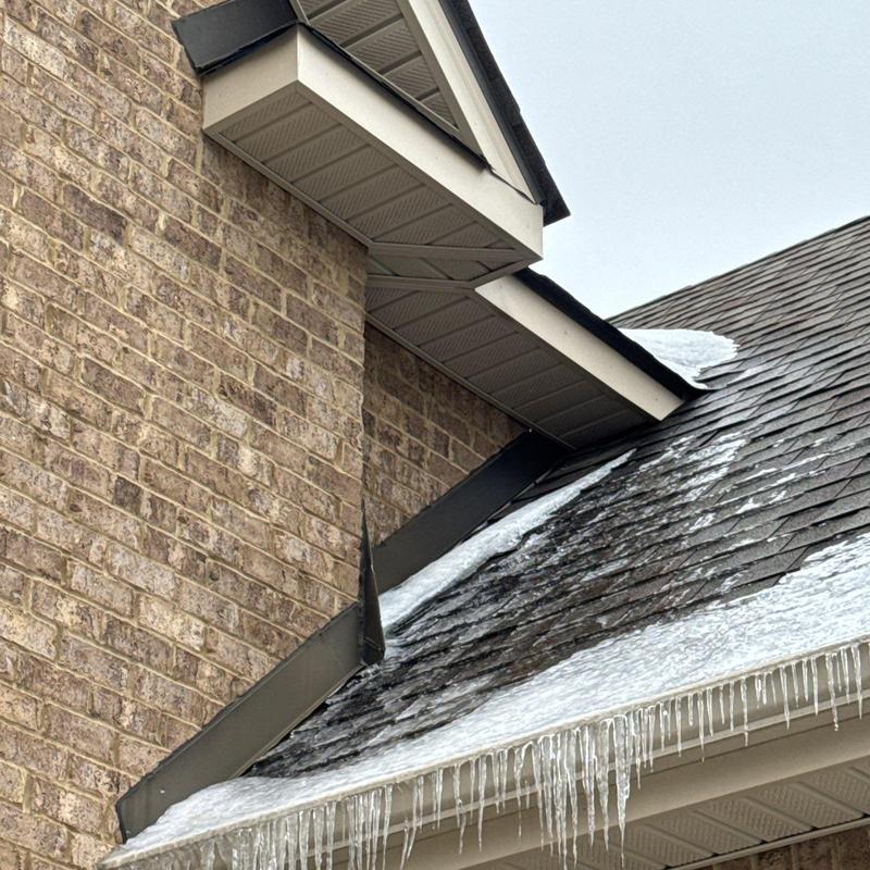 Shingle roof with ice and icicles on flashing