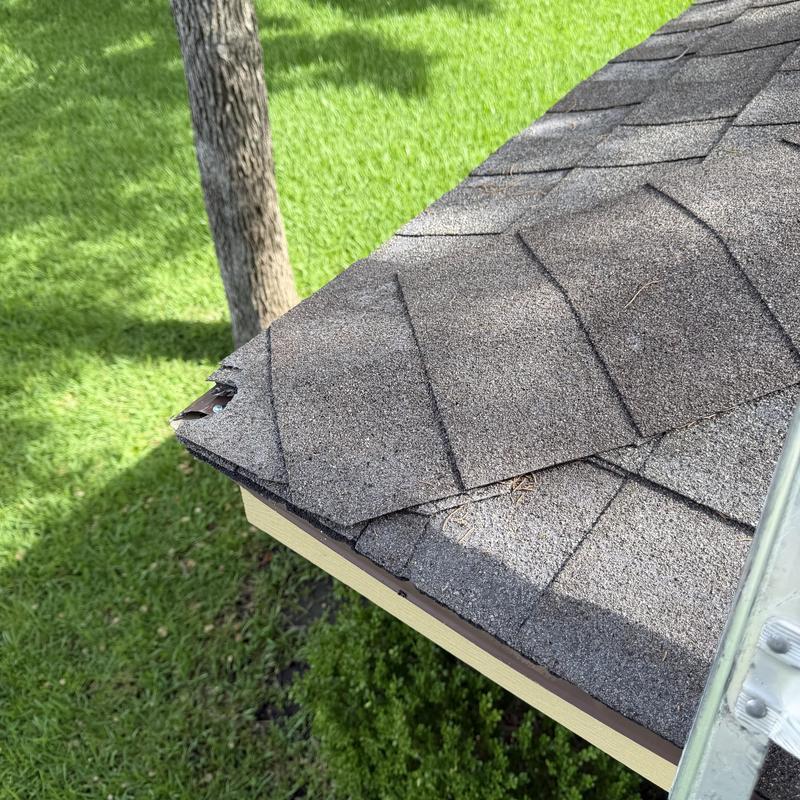 Roof shingles with damaged edges on house roof corner