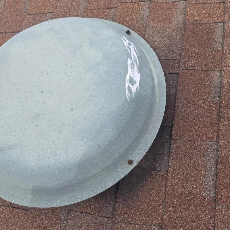 Metal roof vent cap with hail damage on shingles