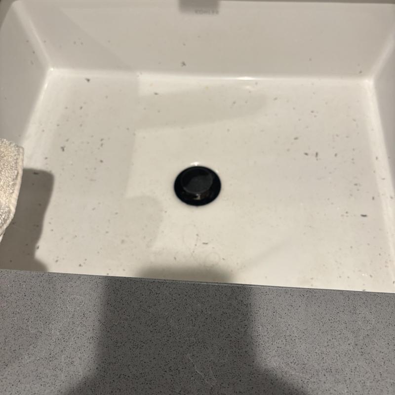 Vanity sink drain with debris and towel nearby