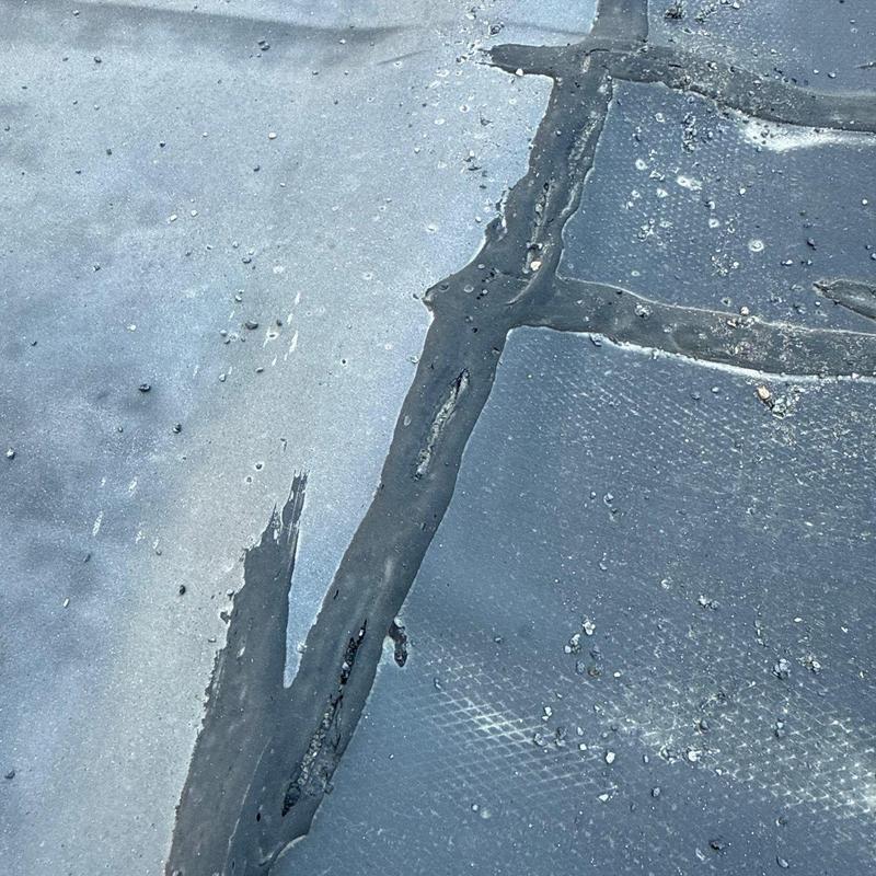 Flat roof membrane showing cracked sealant and damage