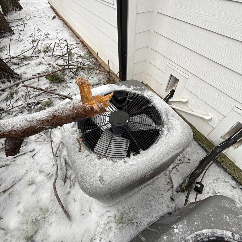 Air conditioning unit with broken tree branch and ice buildup