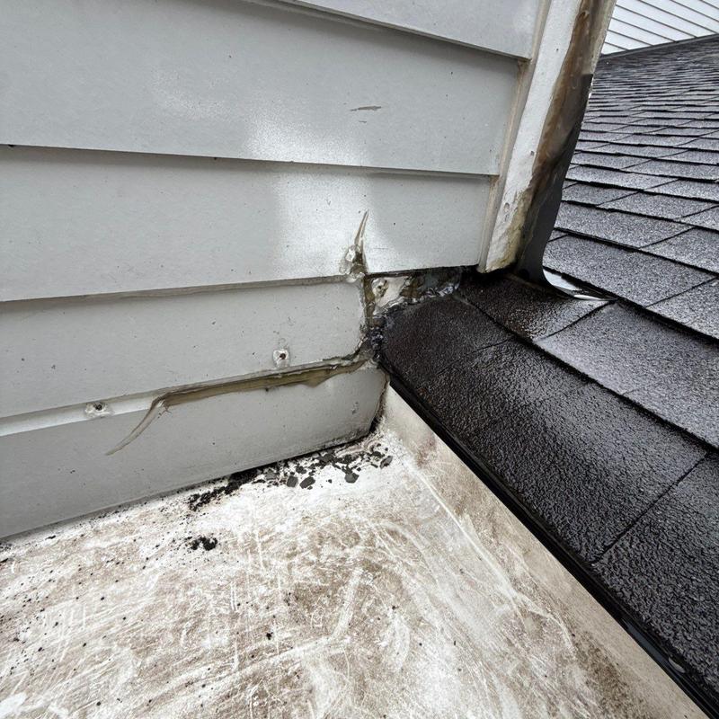 Flashing and siding damage with roof shingles nearby