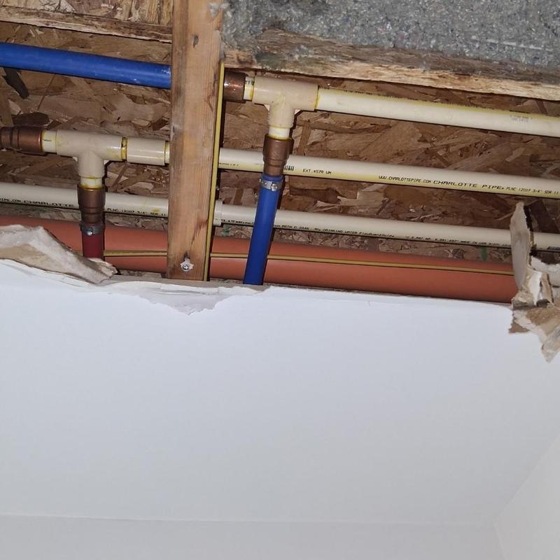 Ceiling water pipes with exposed damaged drywall ceiling