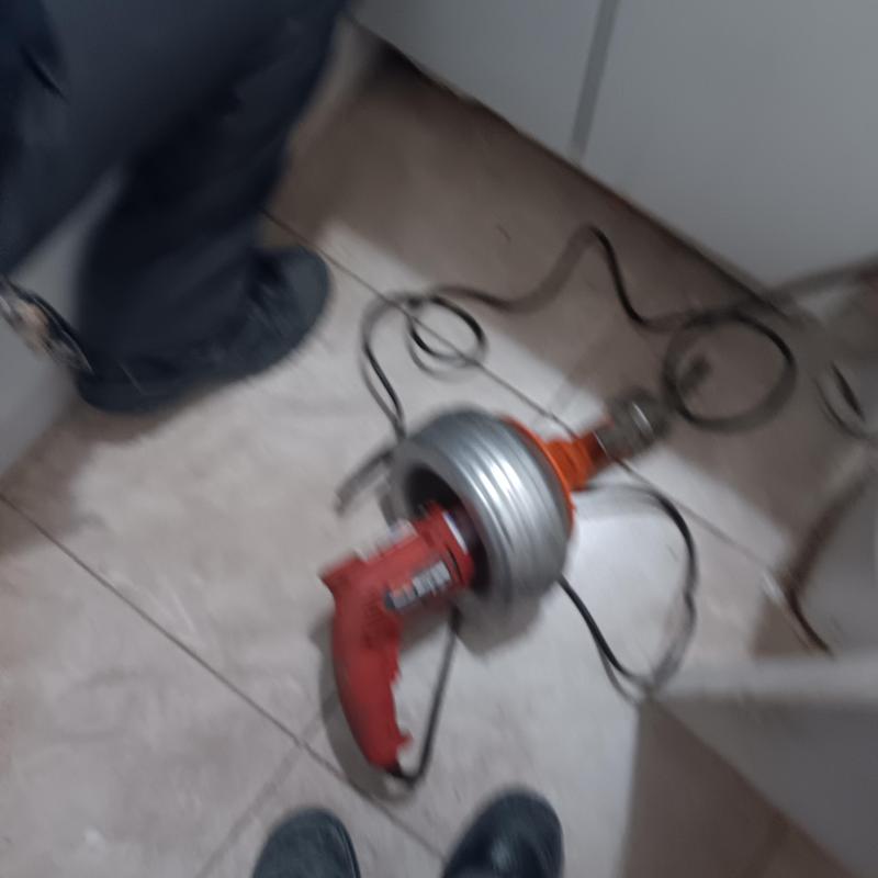Bathtub drain snake tool on tiled floor during plumbing work