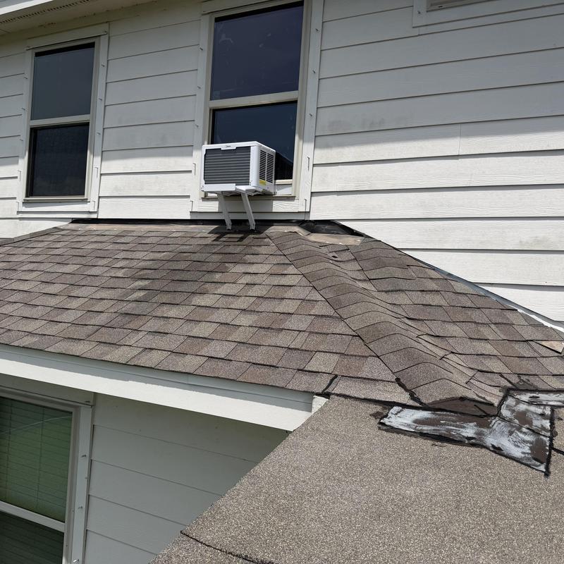 Roof shingles with visible cracks and warping near window AC unit