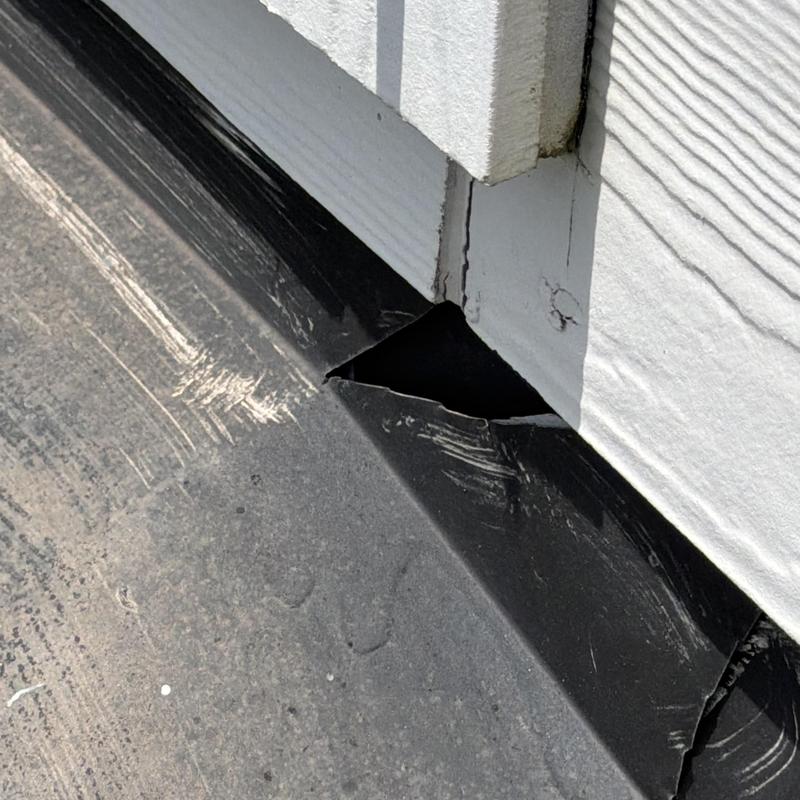 Roof flashing with torn corner near siding joint