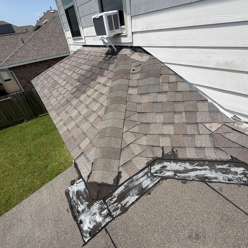 Roof shingles with patched flashing near house wall unit