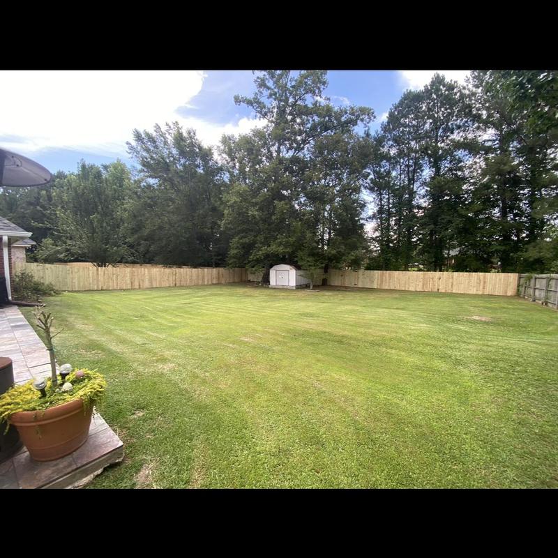 Privacy fence surrounding large backyard with storage shed
