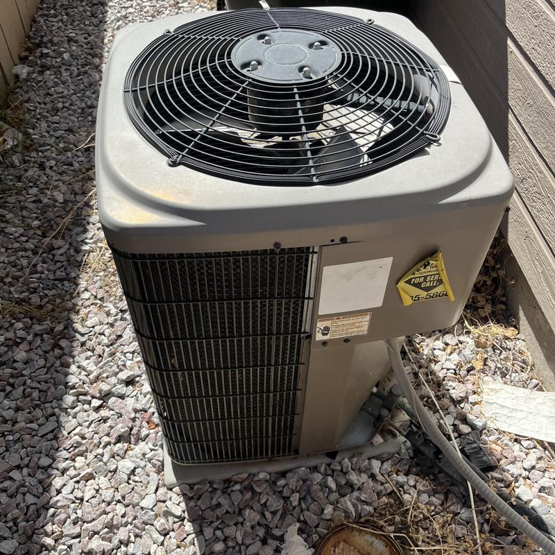 Central air conditioner unit on gravel near wall Central air conditioner unit on gravel near wall