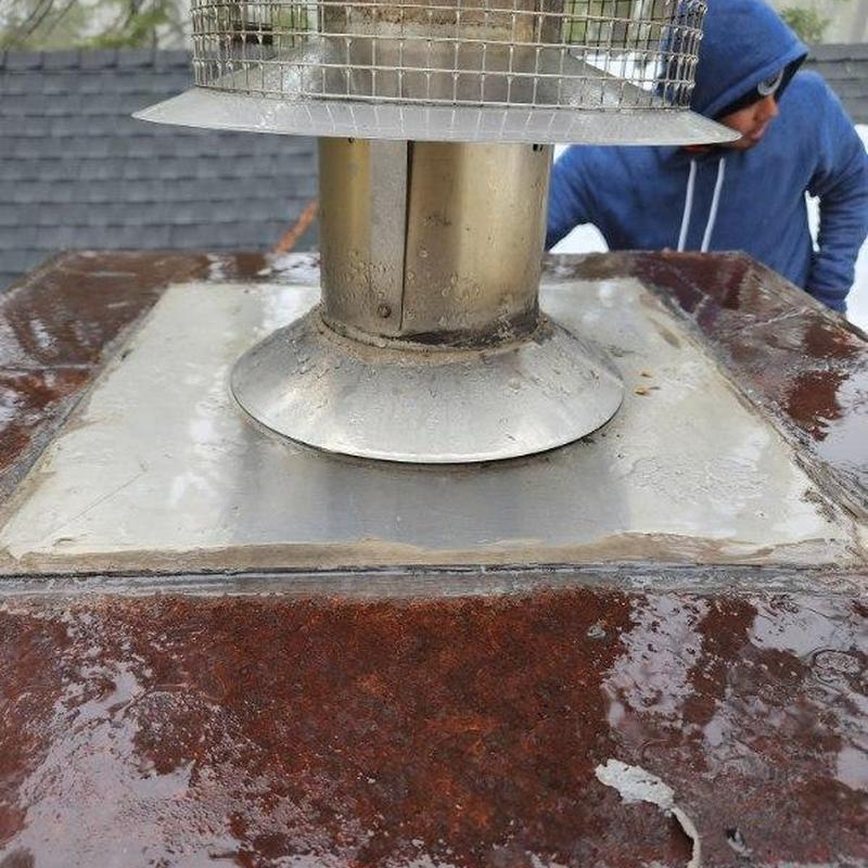 Metal chimney pipe flashing on wet roof with worker