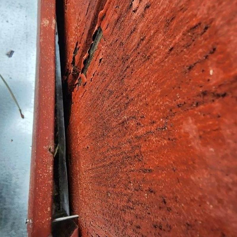 Red wooden siding with damaged and peeling paint