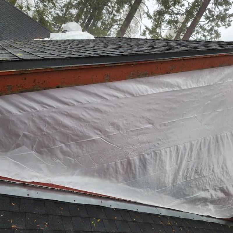 Roof shingles and protective tarp installation on house roof