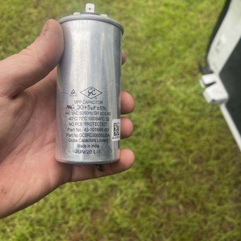 AC condenser start capacitor held in hand outdoors