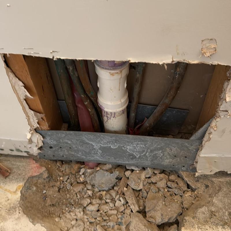 Water supply line below slab with exposed pipes and wall cutout Water supply line below slab with exposed pipes and wall cutout