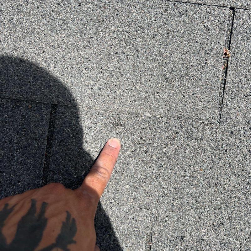 Asphalt shingle roof with hail damage pointed out