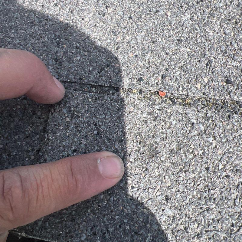 Asphalt shingle roof with visible crack between shingles
