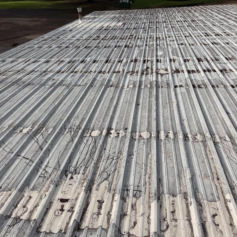 Metal roof with peeling paint before pressure washing