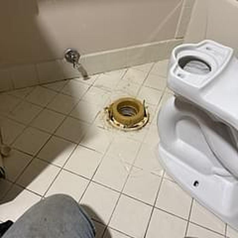 Toilet flange with removed toilet bowl on tiled floor