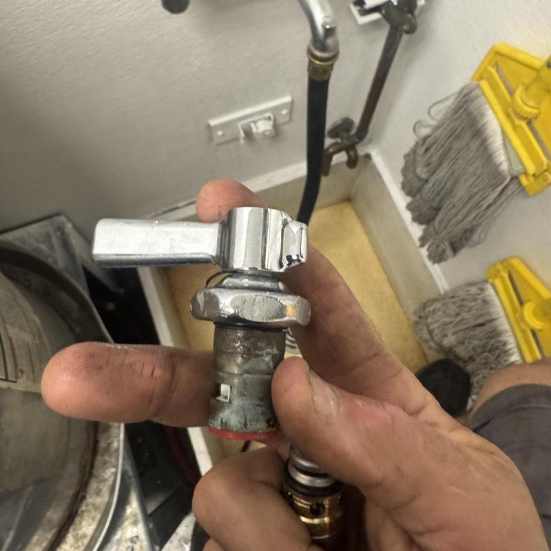 Chicago style faucet valve held in hand near mop sink setup