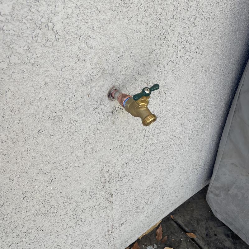 Threaded hose bib with copper pipe fitting on stucco wall