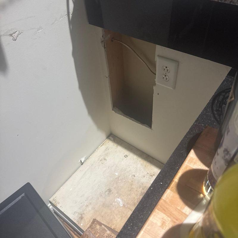 Drywall opening and electrical outlet beside countertop