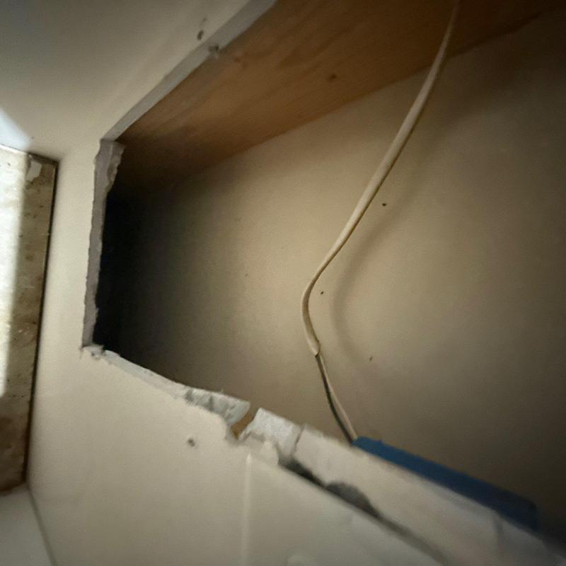 Drywall opening with electrical wiring and damaged edges