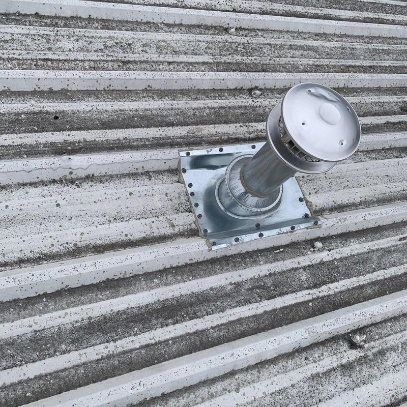 Metal roof exhaust vent with hail damage on commercial roof