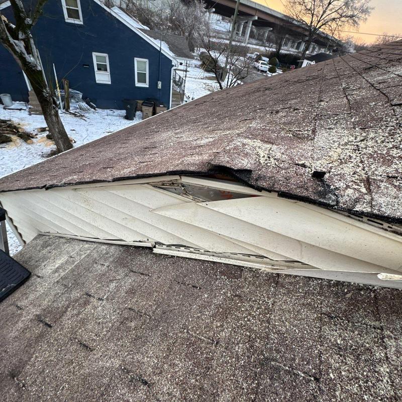 Damaged roof shingles and fascia board with hail impact