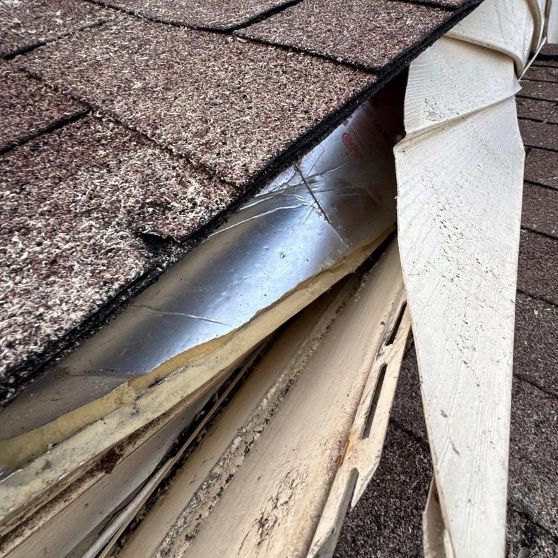 Shingles and damaged roof flashing with exposed metal