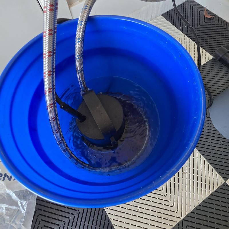 Tankless water heater flushing in blue bucket Tankless water heater flushing in blue bucket