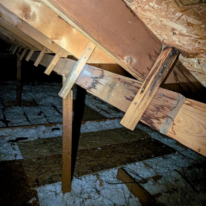 Chimney support beam damage in attic with insulation