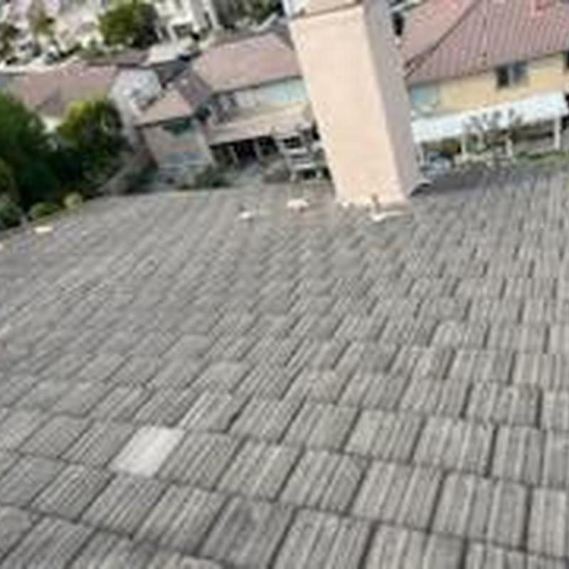 Tile roof with repaired damaged tiles near chimney