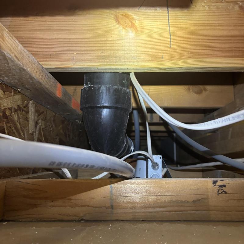 Black PVC drain pipe in wooden joists space