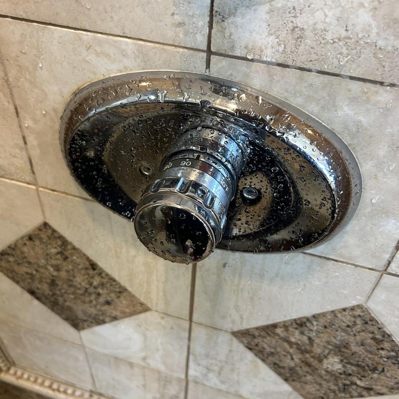 Shower thermostat valve with water droplets on tile wall
