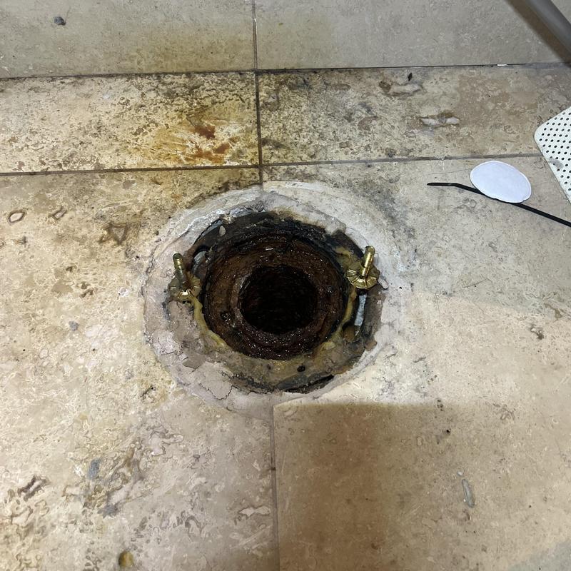 Toilet flange and sewer line opening on tiled floor