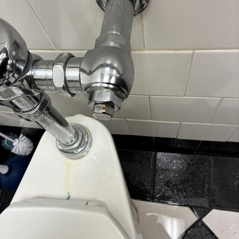 Men's toilet flush valve and plumbing in restroom Men's toilet flush valve and plumbing in restroom
