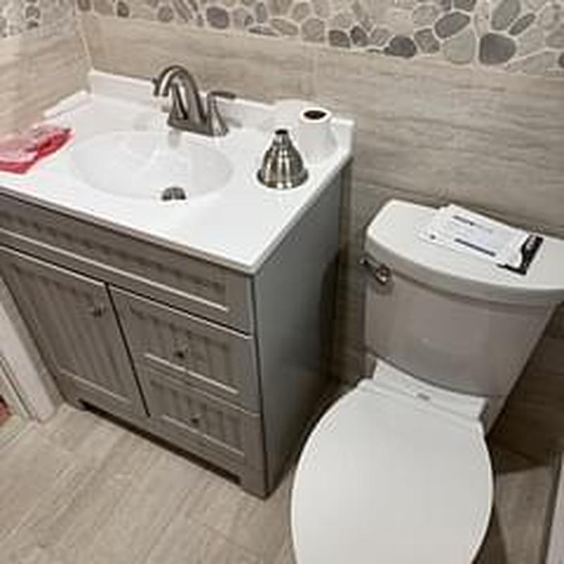 Bathroom vanity sink and toilet installation in tiled bathroom