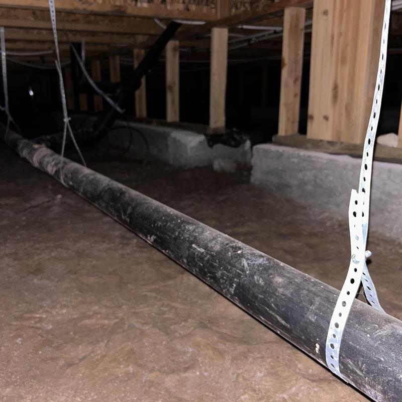 Foundation drainage pipe in crawl space with wood framing